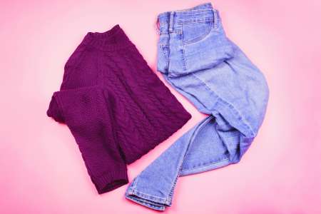 Flat lay of woman clothes with sweater and blue jeans, cozy winter or autumn clothes
